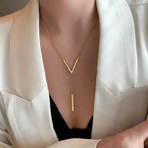 A modern gold Y-bar necklace elegantly drapes on a model wearing a white blazer over a black outfit, showcasing a sleek and sophisticated design.