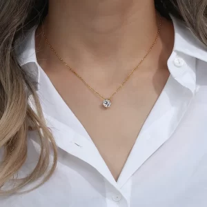 Close-up of a model wearing an 18K gold-plated solitaire pendant necklace with a sparkling cubic zirconia stone, styled with a white button-down shirt for a chic and elegant look.