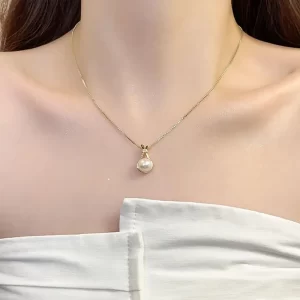 Gold necklace with a pear-shaped pearl pendant, resting gracefully on the neckline.