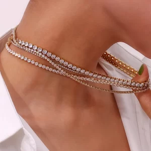 Close-up of a model wearing an 18K gold-plated layered tennis necklace set with sparkling cubic zirconia stones, styled with a white blouse for a chic and sophisticated look.