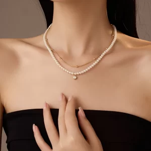 A model wearing an 18K gold-plated double-layer pearl necklace with a crystal pendant, styled with a strapless black top for a chic and sophisticated look.