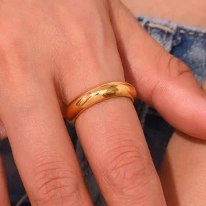 Polished gold ring worn on a finger, highlighting its smooth finish and elegant design.