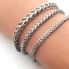 Three stainless steel chain bracelets with different link styles worn on a wrist, featuring a polished silver-tone finish.
