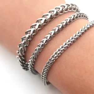 Three stainless steel chain bracelets with different link styles worn on a wrist, featuring a polished silver-tone finish.