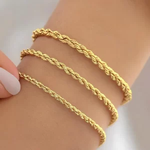 Three gold rope chain bracelets with a polished finish, elegantly worn on a wrist, featuring a delicate twisted-link design.