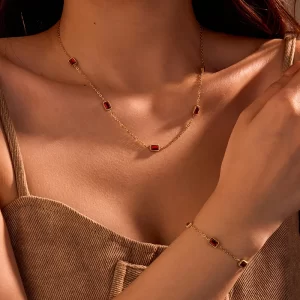 Gold necklace and bracelet set with rectangular red cubic zirconia stones, set in a sleek and elegant design.
