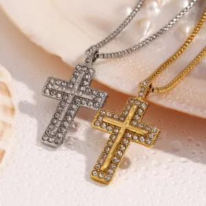 Gold and silver cross necklaces with cubic zirconia crystals, lying on a pearl shell with droplets of water.