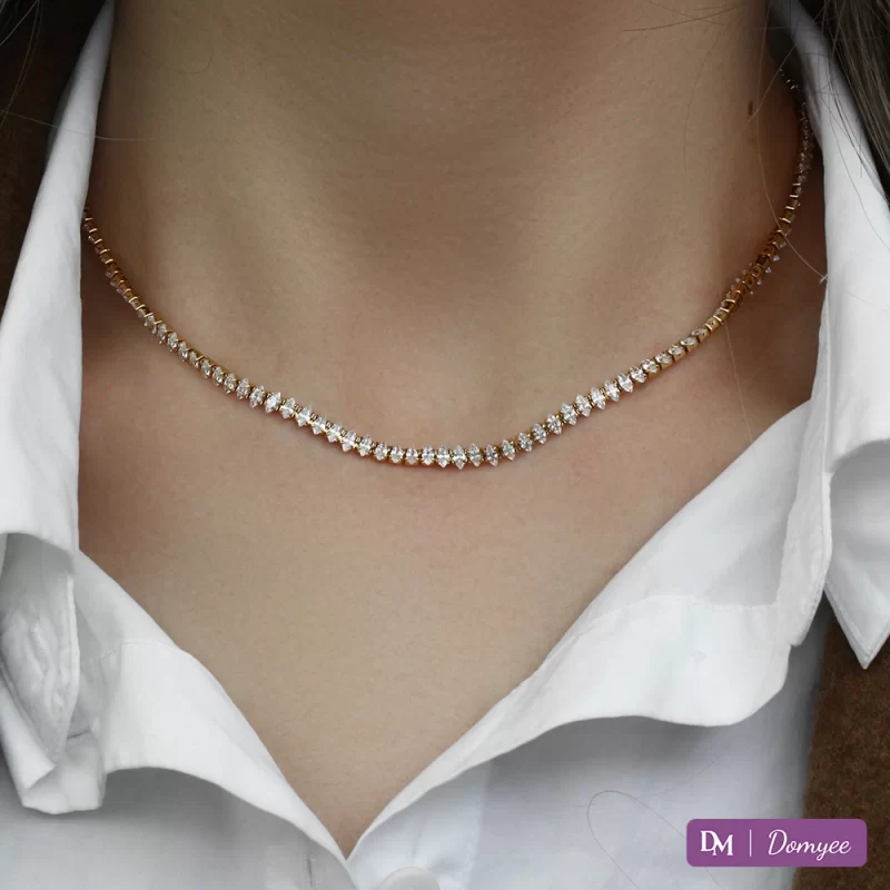 Close-up of 18K gold necklace with marquise-cut cubic zirconia stones, displayed on a black velvet background