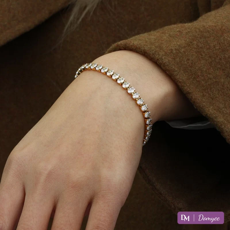 18K gold bracelet with oval cubic zirconia stones, elegantly worn on the wrist, featuring a waterproof, fade-resistant, and hypoallergenic design.