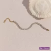 18K gold bracelet with cubic zirconia stones, elegantly displayed on a tabletop with a delicate shell, featuring a waterproof, fade-resistant, and hypoallergenic design.