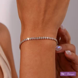 Close-up of 18K gold bracelet with marquise-cut cubic zirconia stones on a wrist, sunlight reflecting off waterproof chain and gem facets.