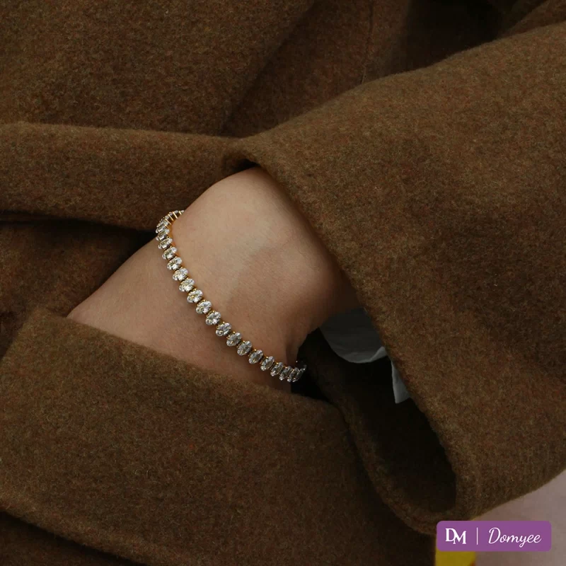 Close-up of a person wearing an 18K gold-plated bracelet with high-quality oval cubic zirconia, showcasing its elegant design and durability.