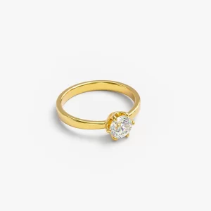 Gold solitaire ring with a diamond displayed on a white surface, highlighting its sparkling beauty.