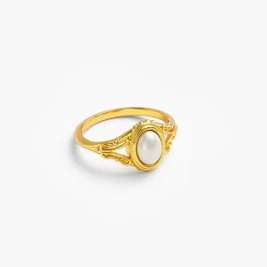 Vintage gold ring with oval pearl accent and intricate detailing.