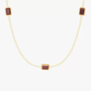Close-up of a gold necklace featuring three red cubic zirconia stones set in rectangular shapes, linked by a delicate chain.